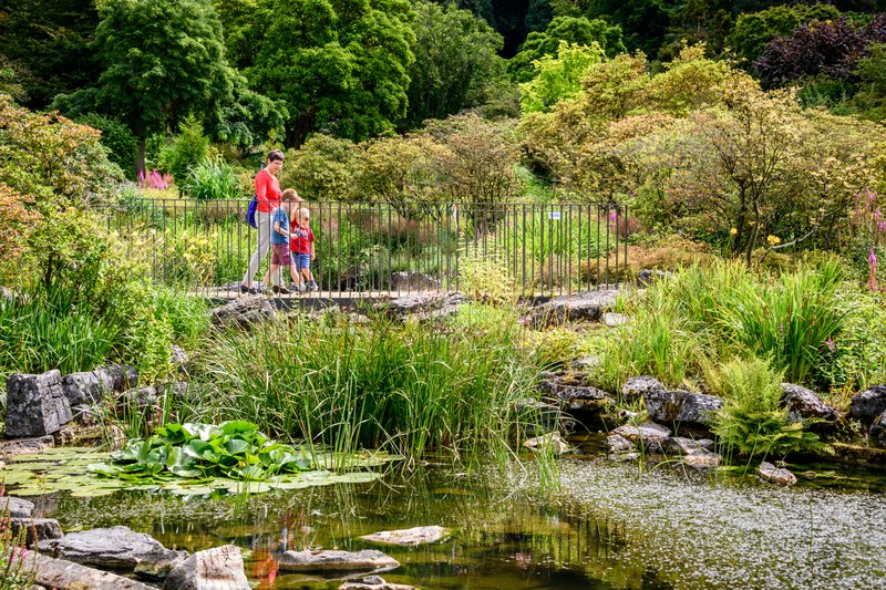 Grootmoeder%20en%20kleinkinderen%20wandelen%20in%20het%20proviciaal%20domein%20van%20Huizingen%20over%20prachtige%20rotsen%20en%20stromend%20water.