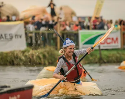 Vrouw in uitgeholde pompoen die aan het peddelen is op het water