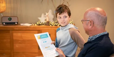 Kleinzoon geeft Vlaanderen Vakantiecheque aan grootvader