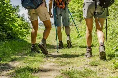 Benen van wandelaars met wandelschoenen en -stokken