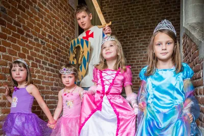 Kinderen verkleed als ridder en prinses wandelen een trap af in een kasteel