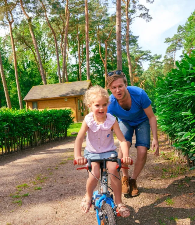 Meisje leert fietsen, papa loopt achter de fiets