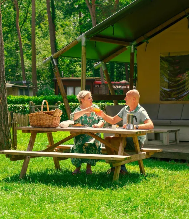 Twee mensen genieten aan een picknick-bank van een ontbijt