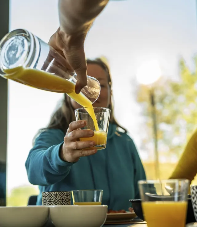 Iemand schenkt het glas van een vrouw in met fruitsap
