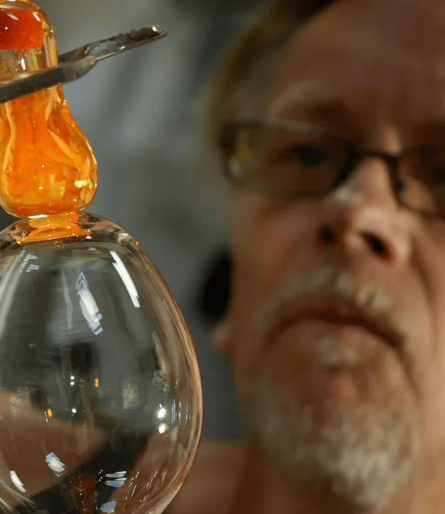 Man kijkt geconcentreerd naar het glas dat hij aan het bewerken is