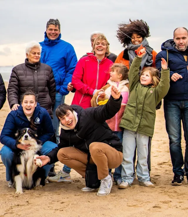 Groepsfoto van een familie met hond op het strand