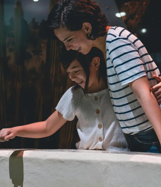 Moeder en dochter kijken lachend naar info in een museum
