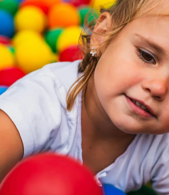 Meisje grijpt naar een bal in het ballenbad