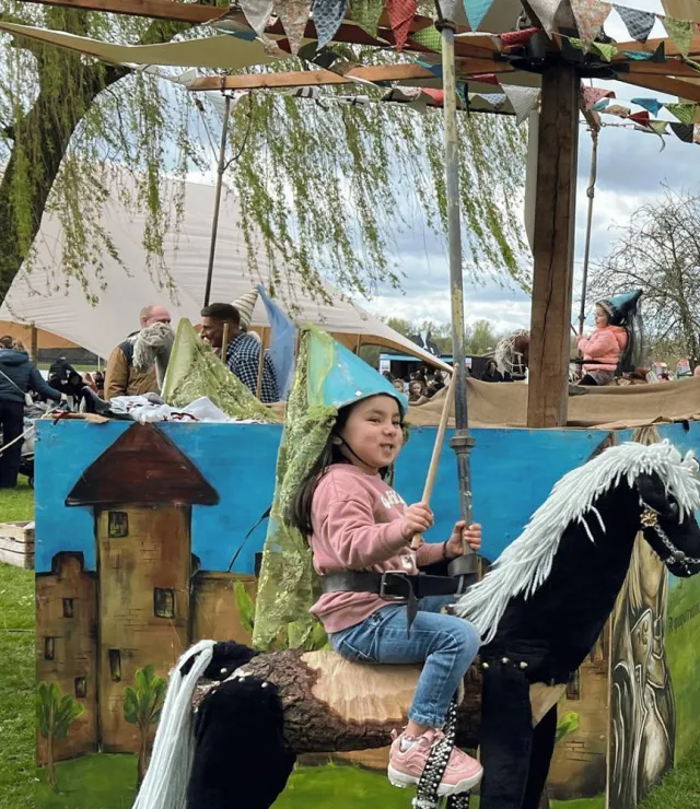 Meisje met tovenaarshoed zit op een paard in een draaimolen