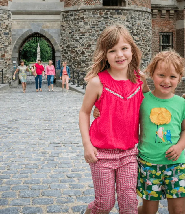 Meisjes omarmen elkaar, in de achtergrond is een kasteelpoort zichtbaar