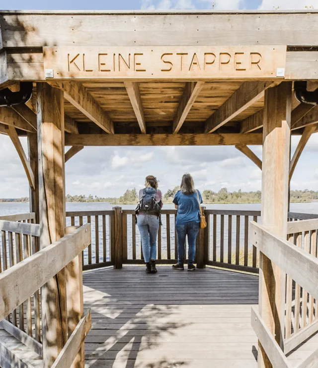 Twee wandelaars genieten van een uitzicht over het water
