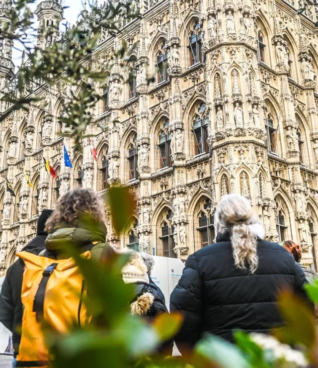 Mensen op de Grote Markt in Leuven kijken naar het Stadhuis