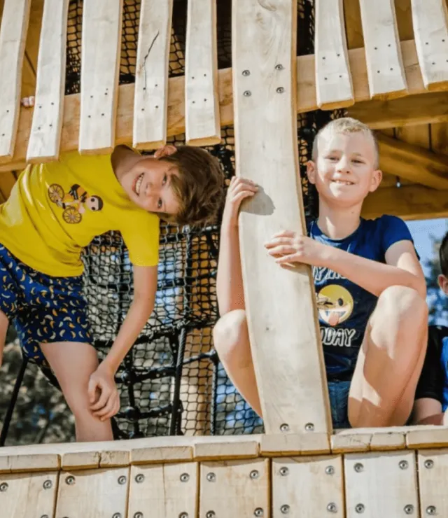 4 kinderen poseren op een houten speeltuig voor de foto